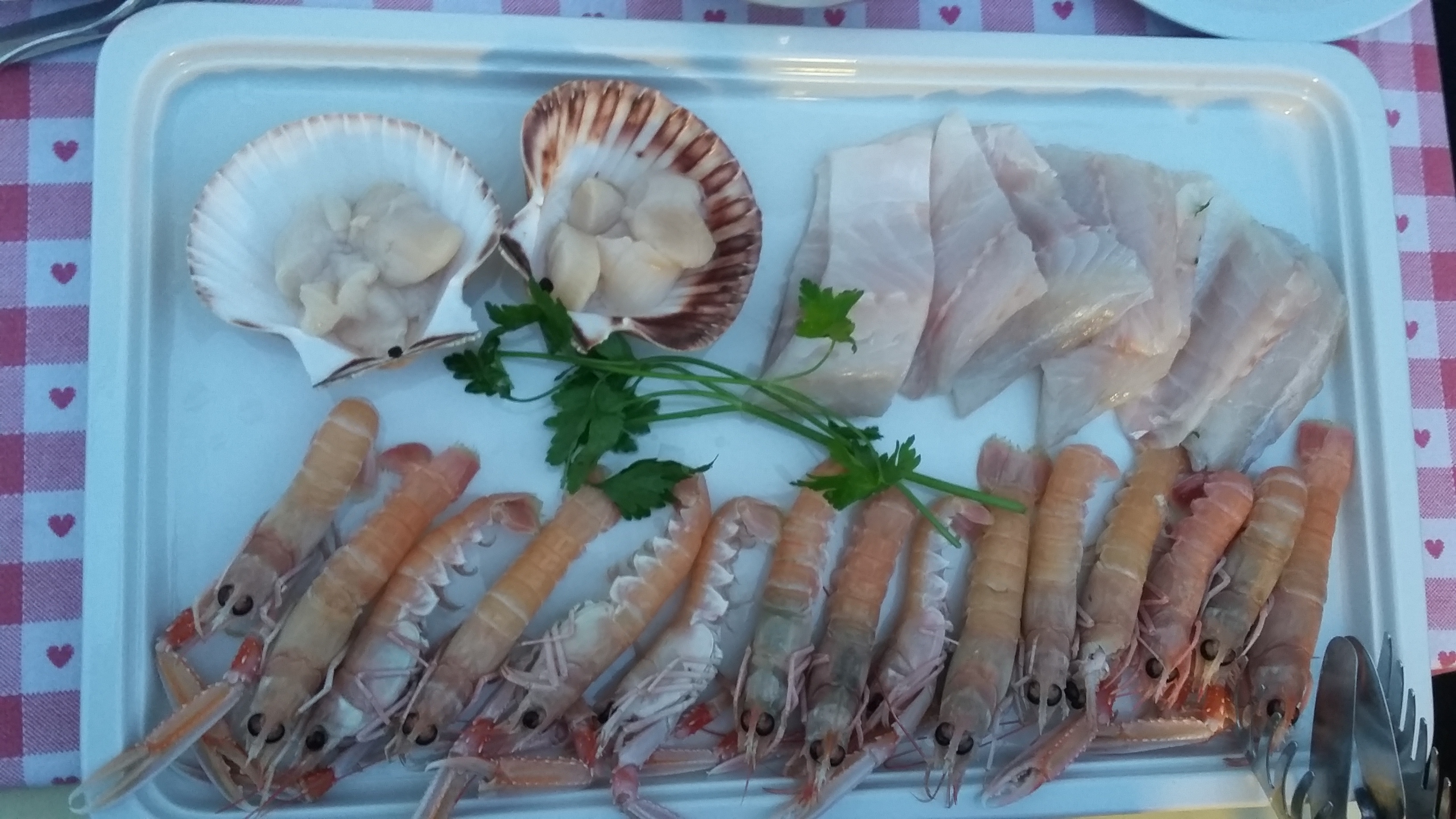  A platter of scampi, branzino filets and scallops waiting to be cooked on a hot salt block. 