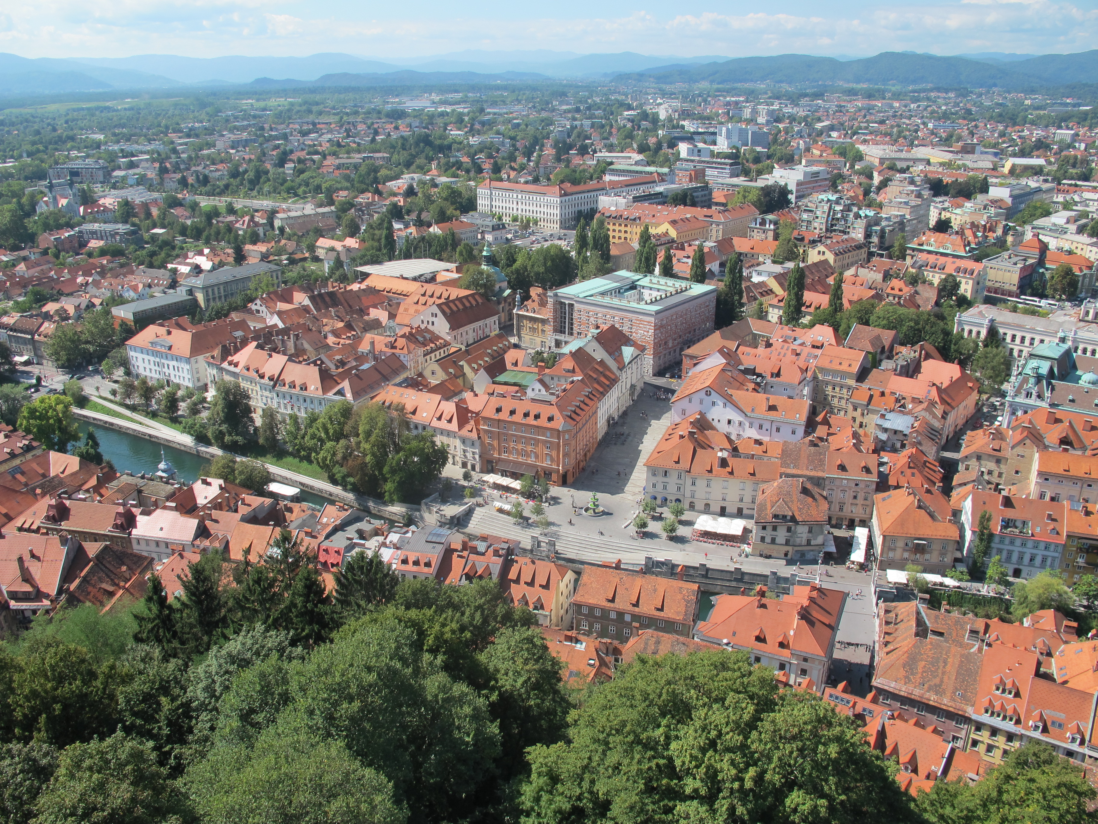 Terra-cotta rooftops, slate green cupolas and river walkways of Ljubljana, framed by the Julian Alps.